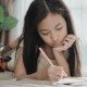 Young teen girl on bed doing homework