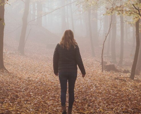 A woman walking alone in foggy woods. We offer young adult therapy in Medford, NJ & Cherry Hill. Start working with a therapist today!