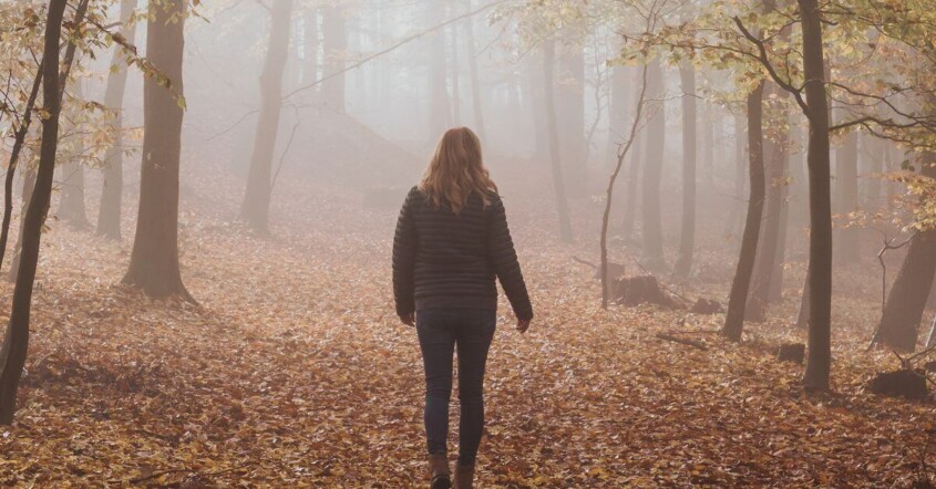 A woman walking alone in foggy woods. We offer young adult therapy in Medford, NJ & Cherry Hill. Start working with a therapist today!