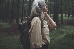 A young thoughtful woman wearing headphones in the forest. Young adult therapy in Medford, NJ can be done online or in person. Get the personalized support you deserve today.