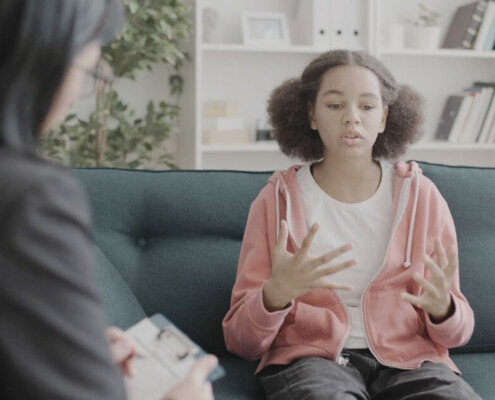 A teen talks expressively with a therapist taking notes nearby. Therapy for teens in Medford, NJ is here to help your child with anxiety & trauma. Get the support they deserve by reaching out to us.