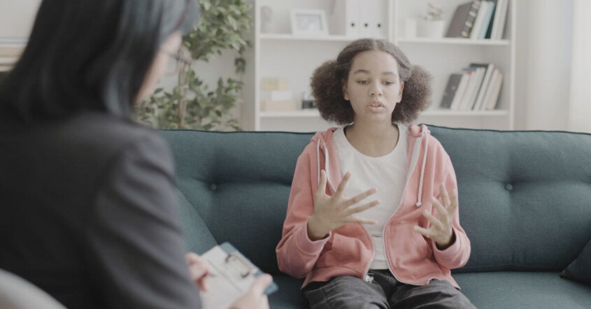 A teen talks expressively with a therapist taking notes nearby. Therapy for teens in Medford, NJ is here to help your child with anxiety & trauma. Get the support they deserve by reaching out to us.