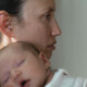 An exhausted-looking new mom holds a sleeping baby on her chest. Motherhood doesn't have to strip you from your identity. Discover how postpartum depression therapy in Haddonfield, NJ can help you find yourself.