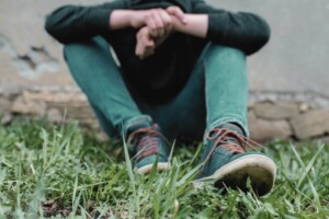 A teenager sits against a wall in the grass with arms crossed. Teen therapy in Medford, NJ & Haddonfield is here to support your teen through life transitions. Reach out today to get started. 