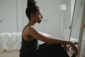 A woman sitting on the floor looking into a mirror thoughtfully. If you're struggling with postpartum depression, we can help. We offer postpartum therapy in Medford, NJ. 