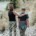 Mom and teen walk side by side on a forest trail, one with an arm around the other.
