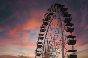 A Ferris wheel stands tall against a colorful sunset sky.