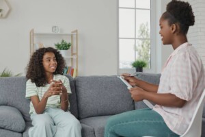 A teenage girl smiles while talking to a therapist.