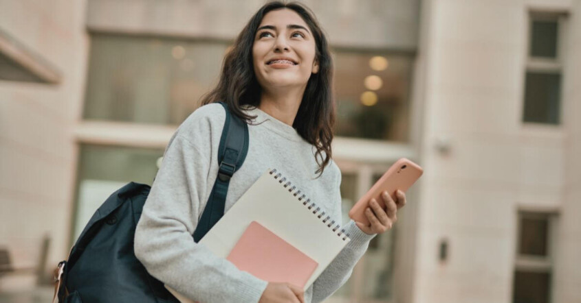 A student walks through campus with a heavy backpack.