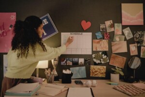 A student writing on a schedule board in a decorated room.