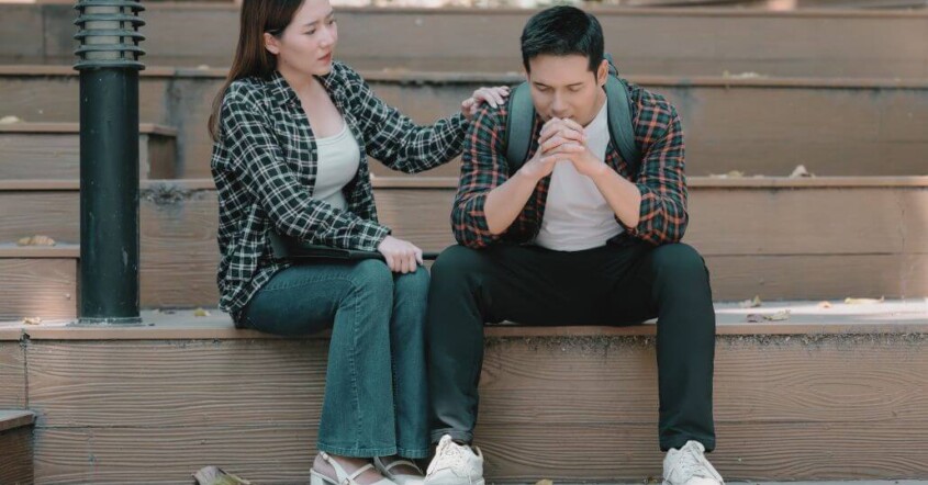 A young college student comforts a distressed male college student.