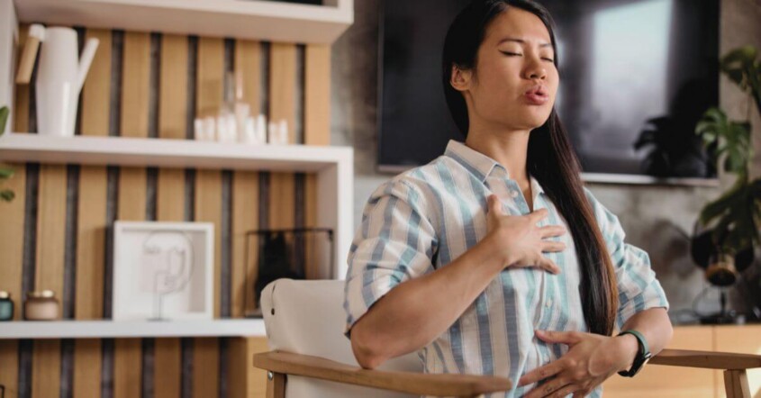 A woman sitting in a chair practices deep belly breathing