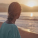 A young woman stands on a beach at sunset, looking out toward the ocean. If you're trying to balance your career, school, & dating, discover how young adult therapy in Cherry Hill, NJ can help you navigate it all.
