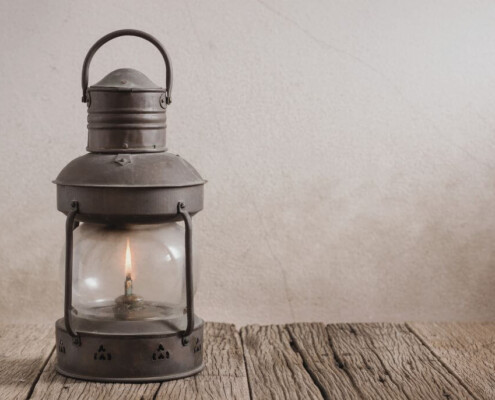 An old-fashioned metal lantern with a small flame inside sitting on wooden table. Young adult therapy in Medford, NJ can help you navigate life transitions. Reach out today to get started.