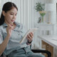 A woman sits at her desk reviewing information on a tablet, with charts and graphs displayed on a computer screen beside her.