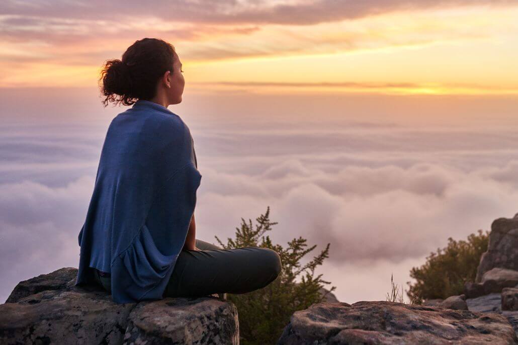 woman sitting on a rock high above the clounds