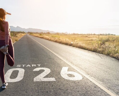 Female runner stretching on empty road with Start 2026 painted on asphalt, symbolizing new beginnings
