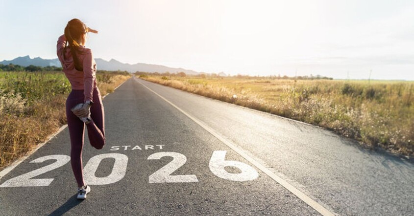 Female runner stretching on empty road with Start 2026 painted on asphalt, symbolizing new beginnings