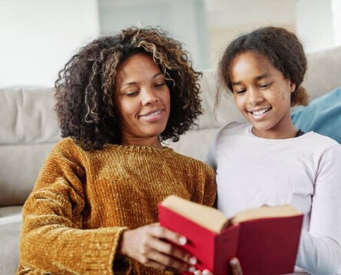 Mother and daughter reading a book together on a sofa, sharing a quiet moment at home