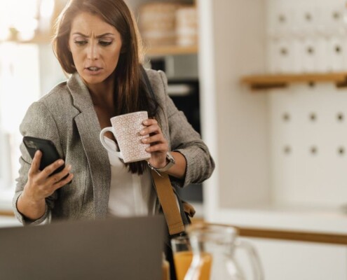 Working woman looking concerned at her phone while holding a coffee mug. Workplace stress & anxiety can increase burnout in women. Discover how women's counseling in Medford, NJ can help you find stress relief strategies.
