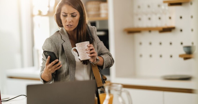 Working woman looking concerned at her phone while holding a coffee mug. Workplace stress & anxiety can increase burnout in women. Discover how women's counseling in Medford, NJ can help you find stress relief strategies.