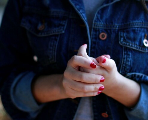 Close-up of a woman’s clasped hands, expressing anxiety, worry, or emotional stress.