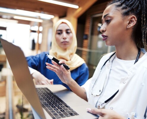 Two female healthcare professionals, including one wearing a hijab, reviewing information on a laptop in a hospital setting. A stressful work environment can impact women's burnout & their anxiety levels. A women's therapist in Medford, NJ can help you find clarity. 