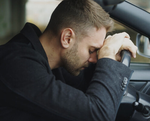 Stressed man resting his head against a steering wheel