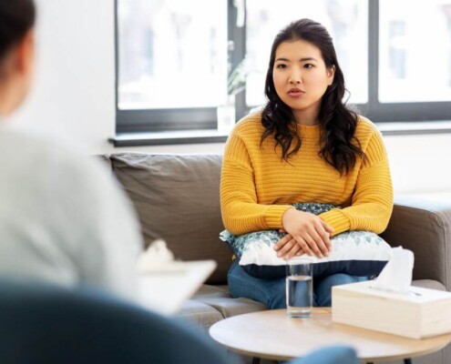 Young woman sitting with therapist talking about stress and mental load, highlighting emotional wellbeing.