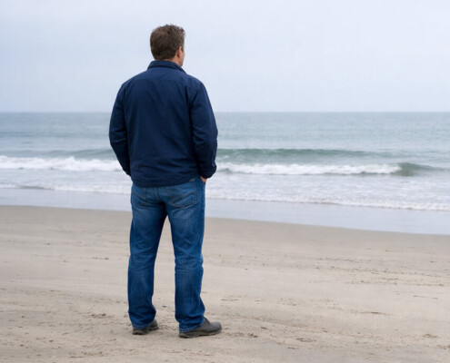 Man standing alone at Wildwood Beach. Hands in pocket, isolated.